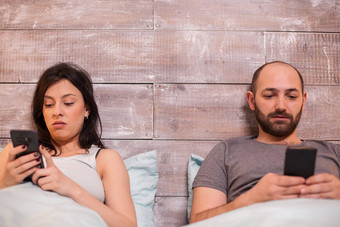 年轻的夫妇床上晚些时候晚上智能手机