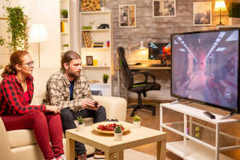 夫妇玩视频游戏大屏幕生活房间晚些时候晚上