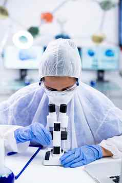 女化学家手套护目镜调整显微镜