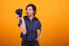 肖像年轻的女摄影师持有相机工作室黄色的背景