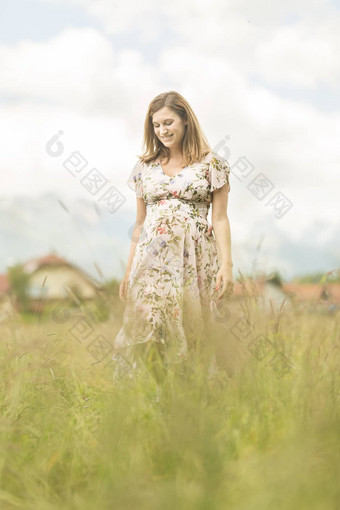 美丽的怀孕了女人白色夏天衣服草地完整的黄色的盛开的花