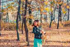 漂亮的黑头发的女孩黑色的夹克蓝色的裙子萨克斯风黄色的秋天公园