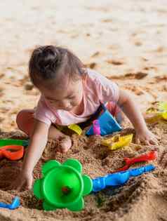 亚洲婴儿女孩玩海滩玩具海滩