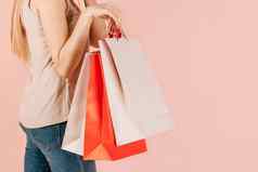 购物消费年轻的美丽的女孩纸袋购物粉红色的背景选择礼物假期购物模拟