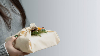 浪费生态友好的圣诞节概念年轻的女人持有手礼物包装自然织物装饰自然材料