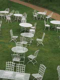 白色金属用板条做的椅子表绿色草坪上砾石路径背景