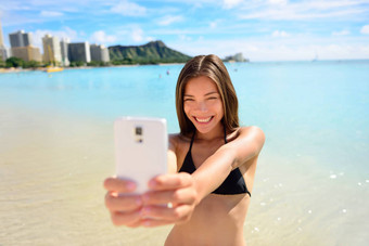 <strong>女孩</strong>采取有趣的智能手机自拍威基基海滩海滩