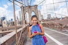 快乐亚洲女人电话发短信布鲁克林桥纽约