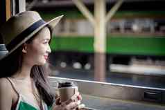 亚洲女人旅行者喝咖啡火车宽松外衣