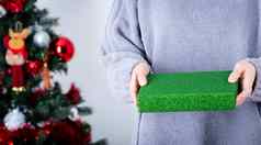 手持有绿色闪闪发光的包装纸圣诞节礼物