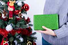 手持有绿色闪闪发光的包装纸圣诞节礼物