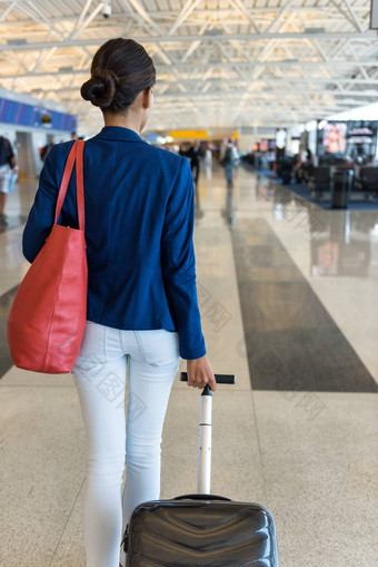 女人旅行者走机场终端门携带钱包随身携带的手行李飞行旅行