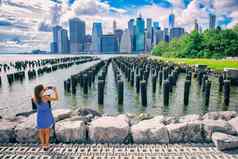 纽约旅游女人采取移动图片智能手机曼哈顿城市天际线海滨生活方式人走享受视图市中心布鲁克林桥公园码头盐沼泽