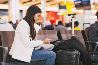 机场女孩乘客移动电话等待延迟飞行坐着终端门luggages无聊累了人