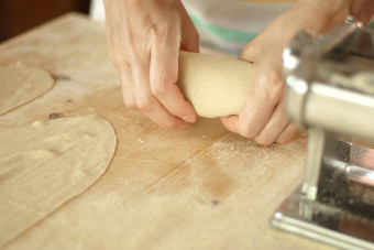 使自制的新鲜的意大利面角视图女人的手揉捏新鲜的意大利面面团木工作表格面粉面团金属手册新鲜的意大利面机