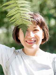 年轻的女人隐藏眼睛蕨类植物叶象征生活