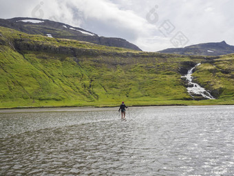 徒步旅行者女人徒步旅行波兰人夹克紫色的他只腿穿越河冰岛角落海滩长途跋涉hornbjarg悬崖瀑布绿色山背景徒步旅行休闲主题