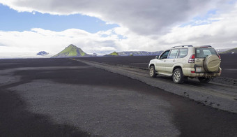 南冰岛自然储备山背7月路车丰田陆地巡洋舰开车污垢山路黑色的熔岩沙子沙漠绿色梅利费尔山片冰川蓝色的天空白色云