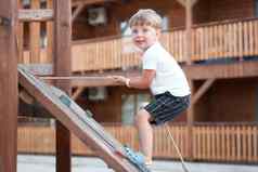 男孩玩操场上孩子攀爬绳子户外孩子们健康的夏天活动