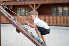 男孩玩操场上孩子攀爬绳子户外孩子们健康的夏天活动