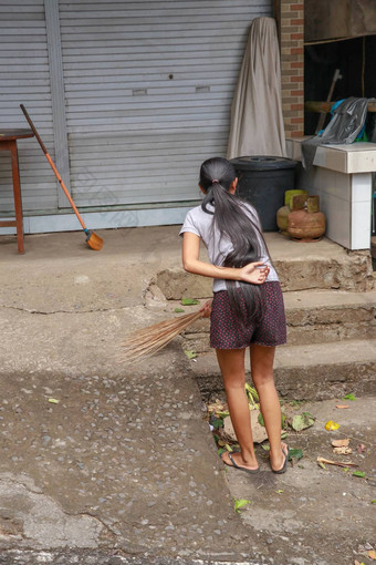 女人清洁服务扫帚坚持簸箕清洁路巴厘岛的女孩清洁工垃圾干叶子前面房子巴厘岛印尼