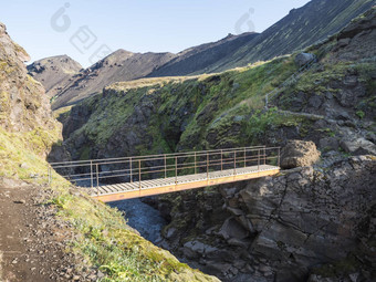 景观木人行桥蓝色的冰川河洛加徒步旅行小道冰岛熔岩形成绿色山山夏天蓝色的天空背景