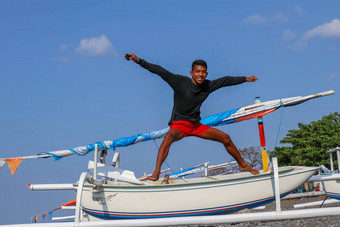 快乐年轻的男人。跳海滩年轻的快乐的印尼<strong>跳跃</strong>少年好情绪<strong>跳跃</strong>空气背景钓鱼船阳光明媚的热带一天蓝色的天空