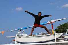 快乐年轻的印尼男人。跳跃海滩少年好情绪跳跃空气阳光明媚的热带一天蓝色的天空