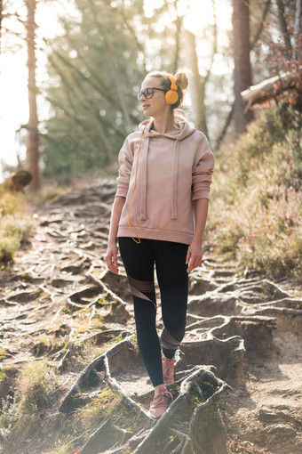 活跃的运动女人听音乐徒步旅行秋天秋天森林女慢跑者培训户外健康的生活方式图像年轻的高加索人女人走徒步旅行小道自然