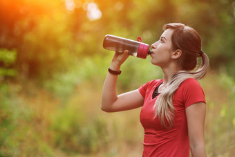 美丽的健身运动员跑步者女人喝水公园水瓶