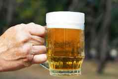玻璃杯子啤酒泡沫男人的手背景自然