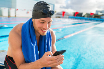 游泳运动员男人。游泳帽护目镜池移动电话发短信智能手机应用程序培训户外池快乐运动员持有手机健身中心