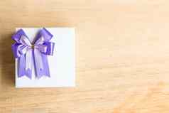 紫色的丝带弓白色礼物盒子木背景
