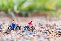 微型人旅行者骑自行车沙子