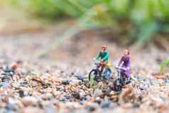 微型人旅行者骑自行车沙子
