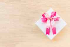 粉红色的丝带弓白色礼物盒子木背景