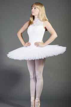 年轻的女芭蕾舞舞者穿图图小心翼翼地灰色背景