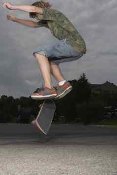 十几岁的男孩跳滑板街一边视图
