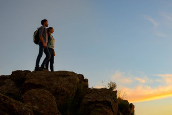 夫妇年轻的旅行者站前岩石夏天日落家庭旅行冒险概念