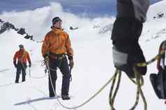 徒步旅行者加入安全行雪山中期部分前面男人。