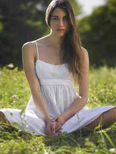 肖像年轻的女人坐着盘腿草地