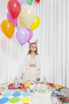 肖像年轻的女孩持有聚会，派对气球蛋糕表格