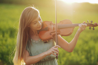 浪漫的女人宽松的头发玩<strong>小提琴</strong>日落光自然