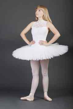 年轻的女芭蕾舞舞者手臀部站灰色背景