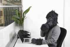 年轻的男人。大猩猩面具挑选鼻子前面移动PC办公室