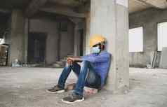 建设工人坐着伤心孤独的工作网站穿医疗面具需要戴安全帽的防止科维德传播概念失业经济危机工作损失冠状病毒危机