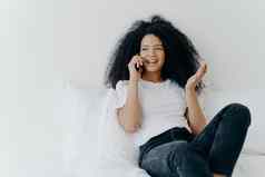人技术沟通休息概念很高兴卷曲的头发的少数民族夫人电话说话手势笑着说快乐花时间首页坐在白色床上