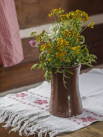 棕色（的）陶瓷花瓶黄色的白色粉红色的场花乡村绣花桌布木表格