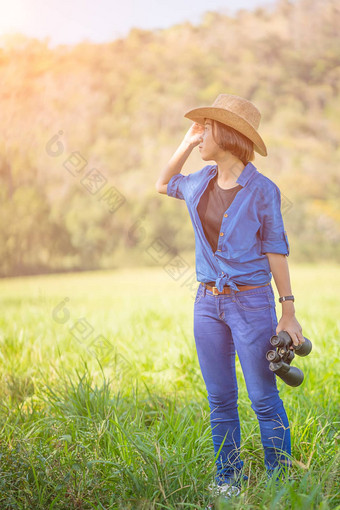 女人穿他持有双筒望远镜草场