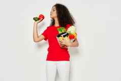 美丽的女人卷曲的头发红色的t恤白色裤子水果蔬菜